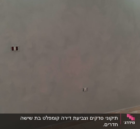 קיר צבוע בגוון אפור עם שקעים חשמליים